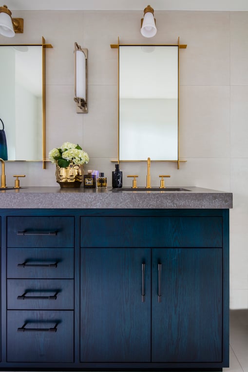 Copper fixtures on a bathroom sink with blue cabinetry designed by Jasmin Reese, Chicago. 