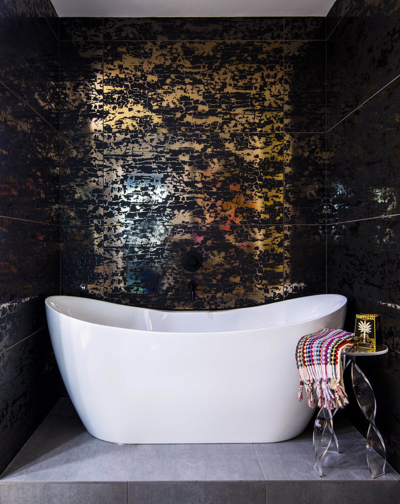 A large porcelain free-standing bathtub with abstract metallic and black wallpaper design by Jasmin Reese, Chicago. 