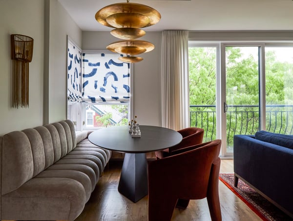 A dining room designed by Jasmin Reese with plush bench seating & a large unique gold chandelier, Chicago. 