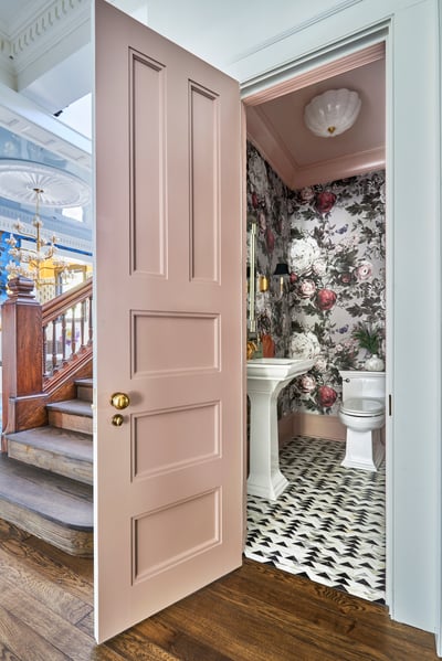 A peach, black, and floral powder room designed by Jasmin Reese with a pedestal sink and toilet, Chicago. 