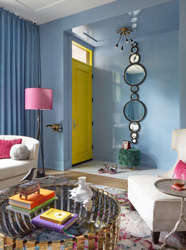 A bright chartreuse door with a circular mirror in detail in a blue living room designed by Jasmin Reese Interiors, Chicago, USA. 