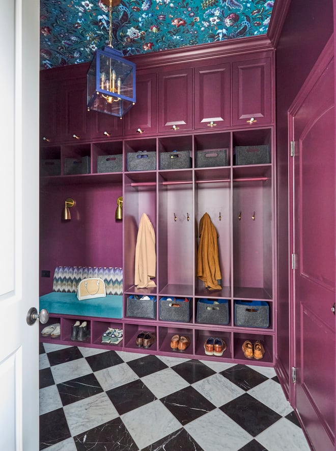 A front view of a kid's locker room style mudroom painted metallic magenta with black and white checkered marble flooring - interior design by Jasmin Reese Interiors, Chicago, USA. 