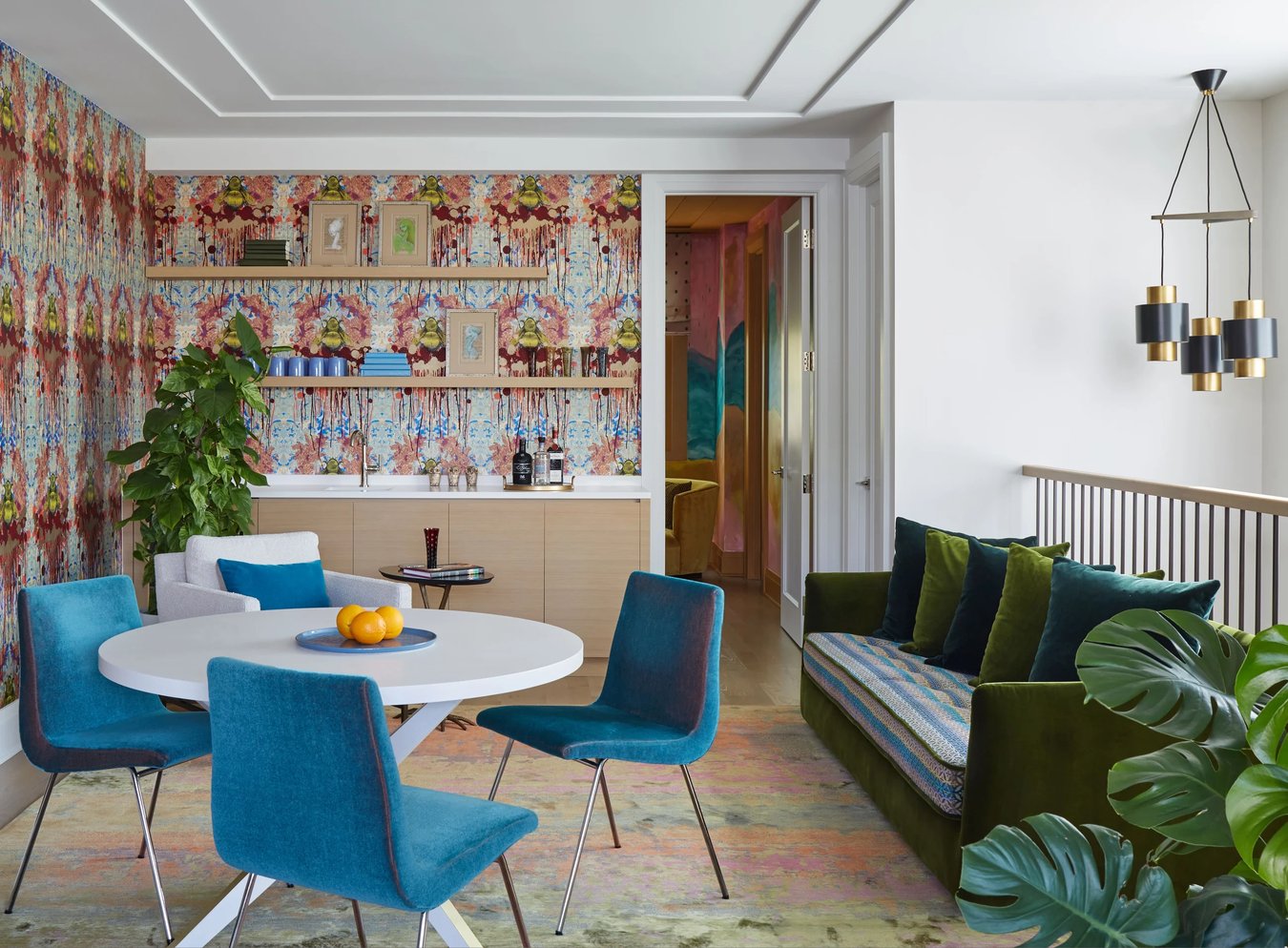 A small dinette with blue velvet upholstery in a wet bar designed by Jasmin Reese: ink-blot colorful wallpaper. 