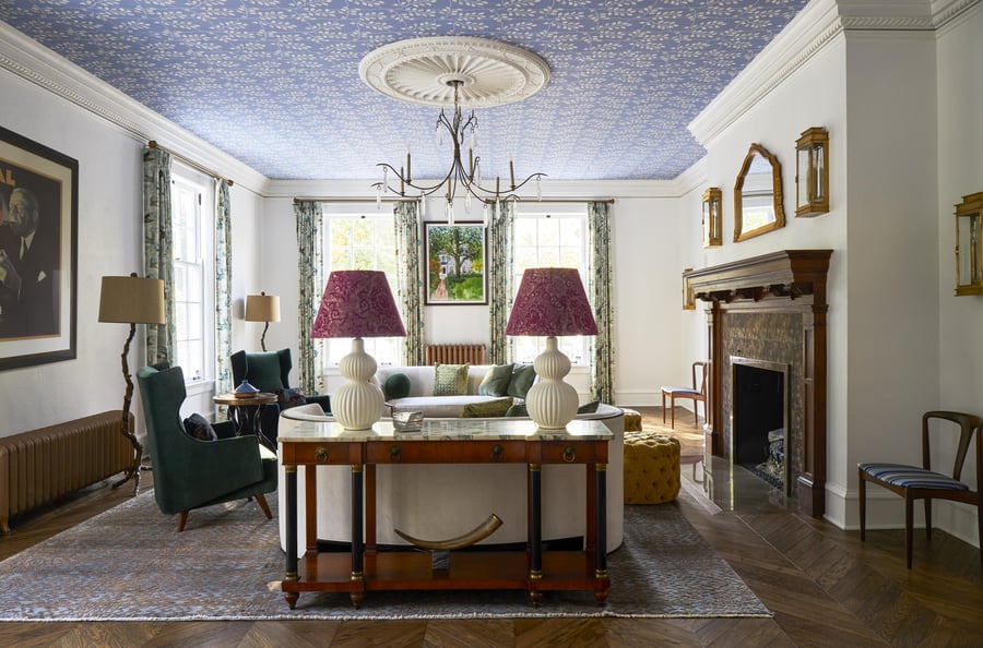 Turn-of-the-century living room that reveals a periwinkle and white floral print on the ceiling with a crystal chandelier and two red paisley lampshades on modern-style white lamps on a marble sideboard - living room design by Jasmin Reese Interiors, Chicago, USA. 