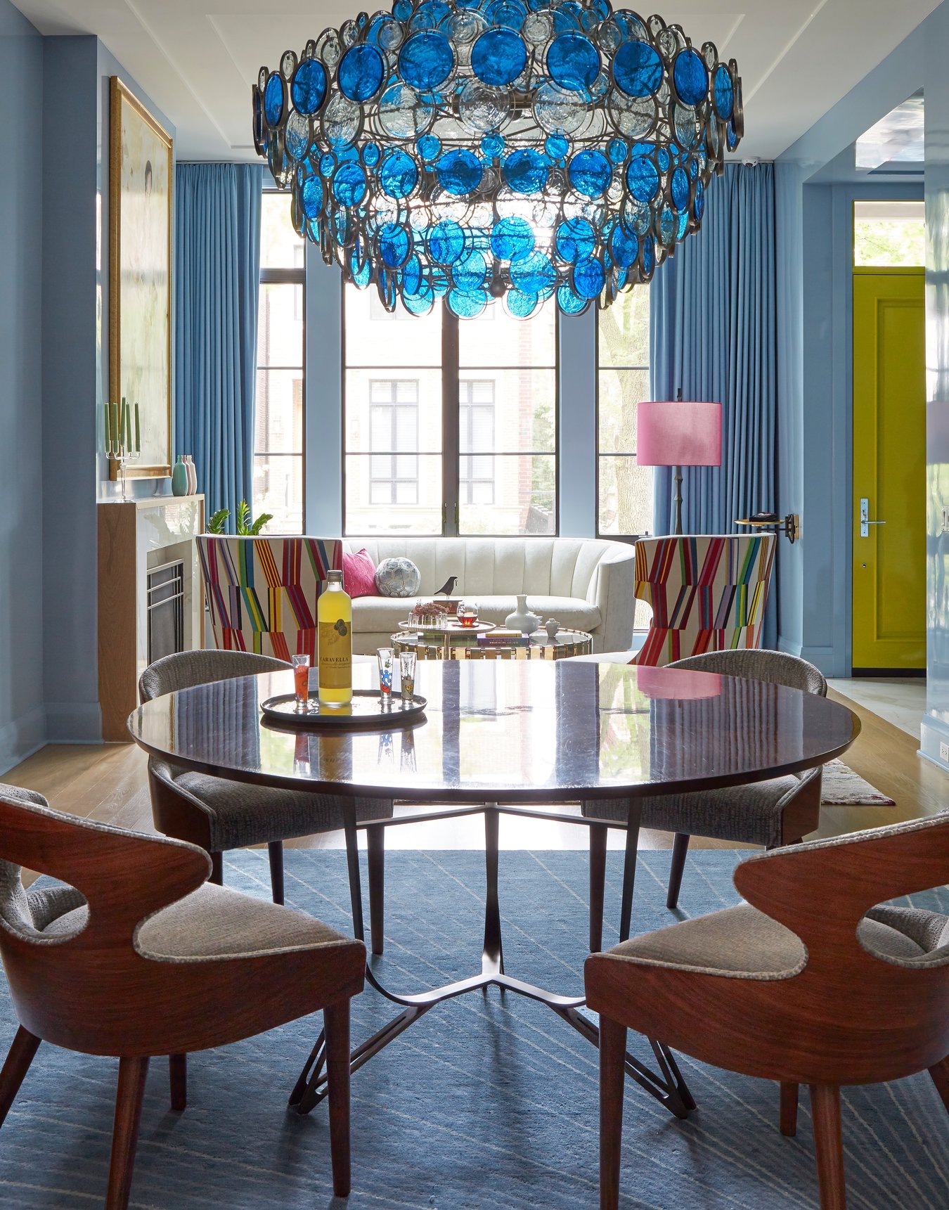 A blue and white glass chandelier in a living room with bright natural light and blue drapes designed by Jasmin Reese Interiors, Chicago, USA. 