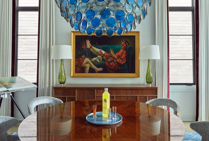 A dining room designed by Jasmin Reese with a modern painting above an art deco sideboard, Chicago. 