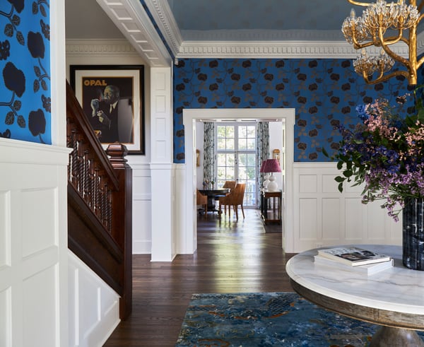 A small dining area and living room seen from a bright blue, gold, and white anteroom with wooden floors - designed by Jasmin Reese Interiors, Chicago, USA. 