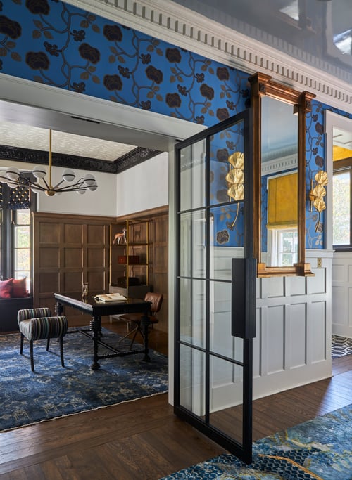 A large study in brown and blue as seen from an anteroom with white, gold, and bright blue wallpaper and paint - designed by Jasmin Reese Interiors, Chicago, USA. 