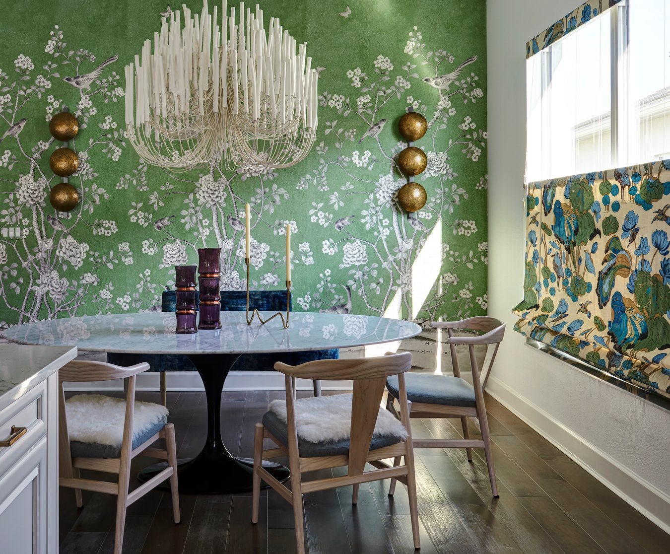 A dining room designed by Jasmin Reese with green scenic wallpaper and unique white candelabra, Chicago. 