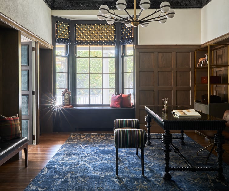  A large study with a window seat, dark wood furniture, blue rug, and hardwood floors - interior design by Jasmin Reese Interiors, Chicago, USA. 