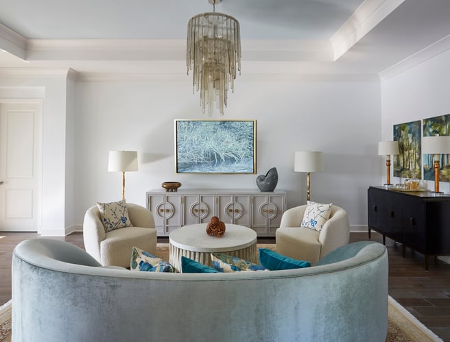 The back of a circular, seafoam green velvet sofa with two circular armchairs in a large white living room with a glass and gold chandelier - living room design by Jasmin Reese Interiors, Chicago, USA. 