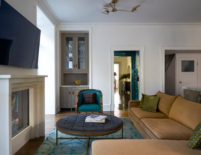 A large gold sectional sofa in a large white living room with a flatscreen tv over a modern white fireplace - living room design by Jasmin Reese Interiors, Chicago, USA. 