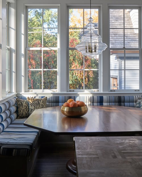 A kitchen nook dinette with bench seating in front of a large window by Jasmin Reese, Chicago. 