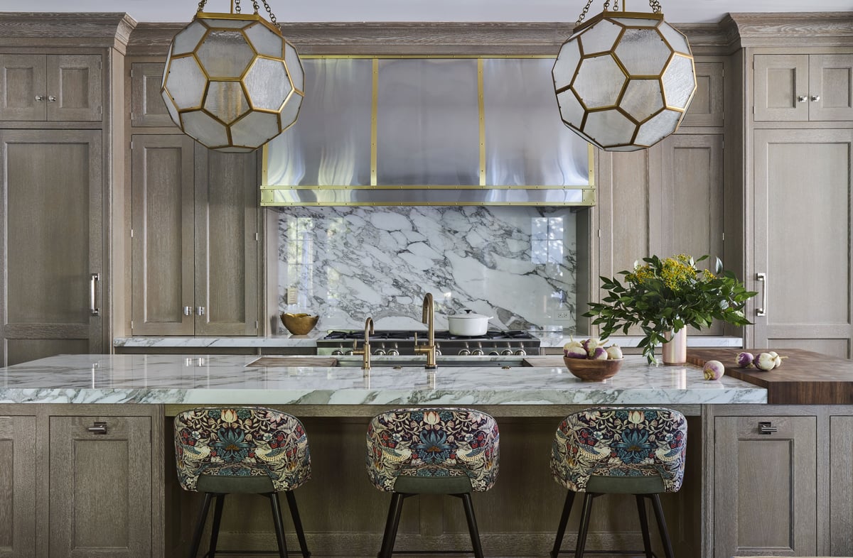 A large tradition kitchen with marble countertops with floral barstools designed by Jasmin Reese, Chicago. 