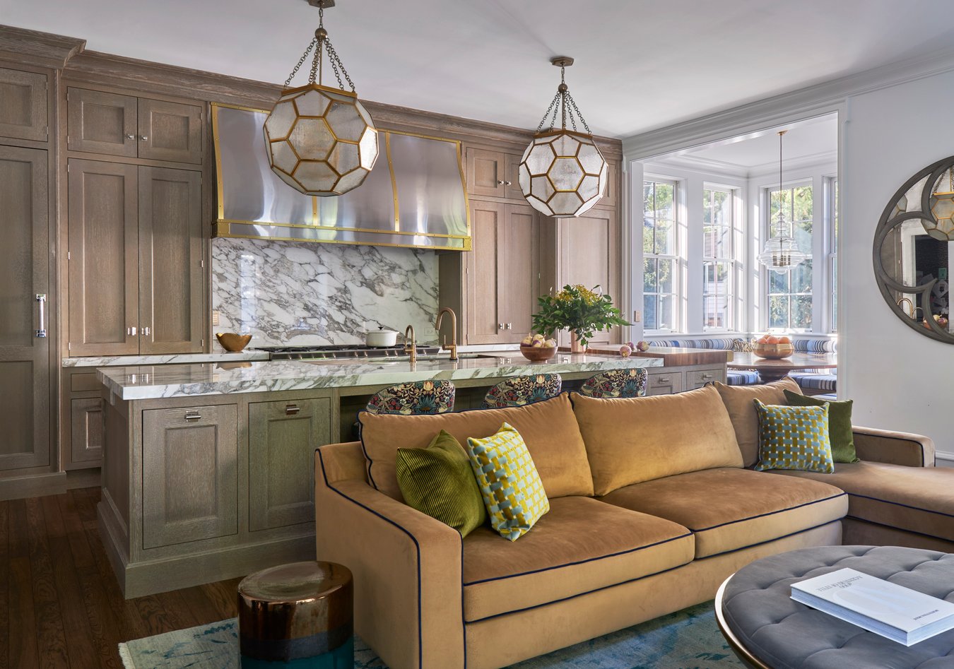 A large gold sectional sofa beside a large kitchen designed by Jasmin Reese, Chicago. 