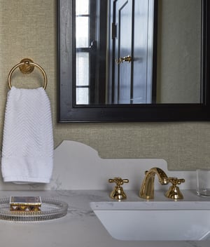 Antique copper fixtures and angular marble backsplash accent a small bathroom designed by Jasmin Reese, Chicago. 
