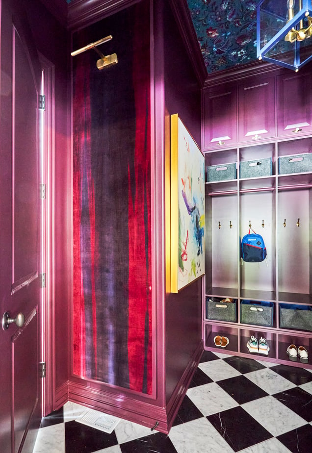 A side view of a kid's locker room style mudroom painted metallic magenta with black and white checkered marble flooring - interior design by Jasmin Reese Interiors, Chicago, USA. 