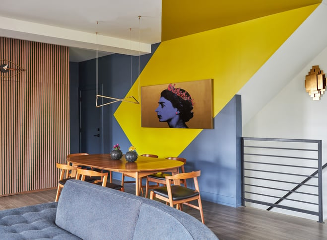 A modernist dining room designed by Jasmin Reese with minimalist wood dinette and bright yellow & blue geometric paint, Chicago. 