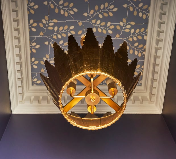 A gold crown chandelier in an entryway designed by Jasmin Reese Interiors, Chicago: crown molding, wallpapered ceiling. 
