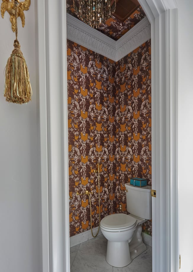 A small bathroom with brown and orange wallpaper designed by Jasmin Reese, Chicago. 