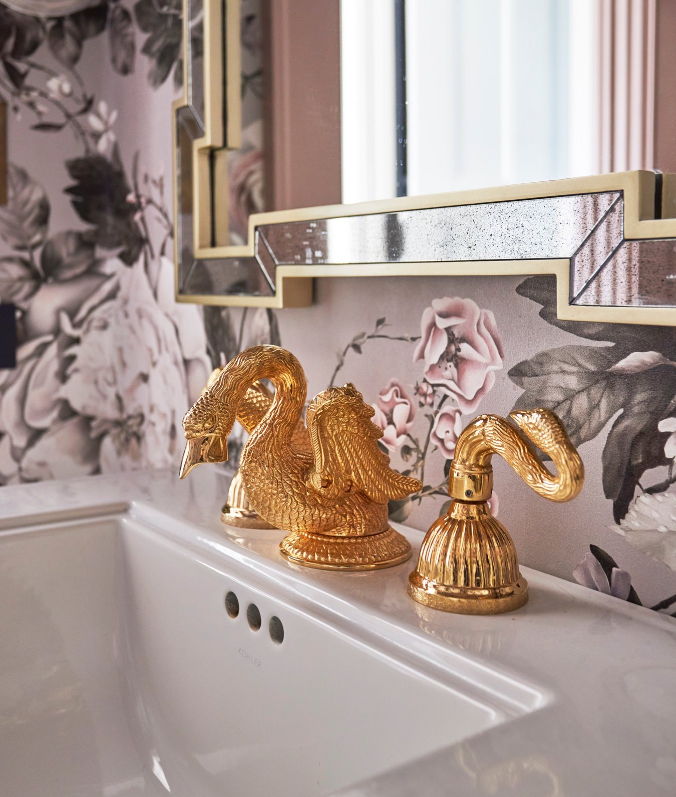 A brass swan sink fixture on an angular sink in a powder room designed by Jasmin Reese, Chicago. 