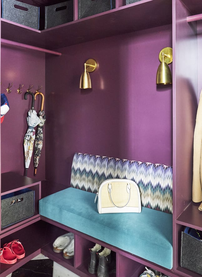 A turquoise velvet bench in a kid's locker room style mudroom painted metallic magenta with black and white checkered marble flooring - interior design by Jasmin Reese Interiors, Chicago, USA. 