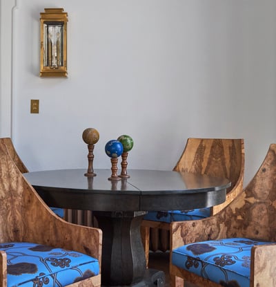 A side view of wooden chairs with natural patterns and bright blue cushions around a black marble table in a white room - living room designed by Jasmin Reese Interiors, Chicago, USA. 