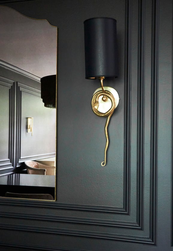 A wall sconce with a gold serpent design in a dining room by Jasmin Reese, Chicago. 