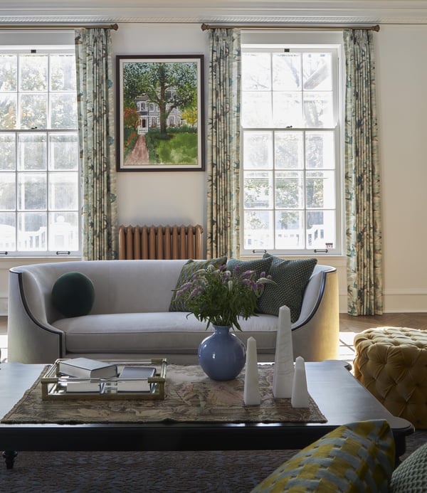Turn-of-the-century living room with a large, rounded cream sofa with dark wooden accents with a painting of a home as the focal point - living room design by Jasmin Reese Interiors, Chicago, USA. 