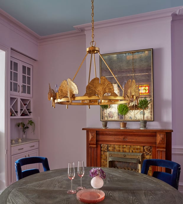 A dining room design by Jasmin Reese with pink walls and an antique wooden fireplace mantle, Chicago. 