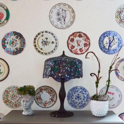 A stained glass lampshade with antique plates on the wall - interior design by Jasmin Reese, Chicago. 