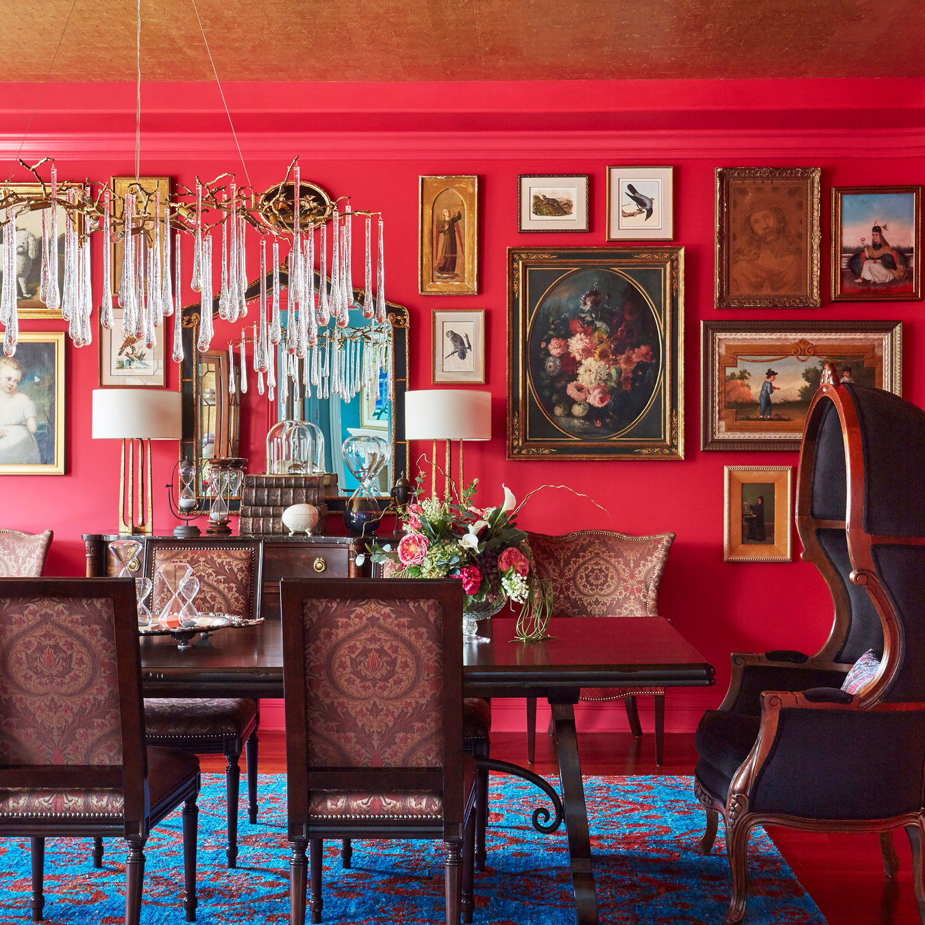 A bright red formal dining room with Victorian furniture and portraits designed by Jasmin Reese, Chicago. 