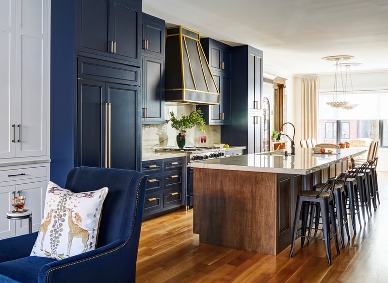 A large kitchen design by Jasmin Reese with blue and gold cabinetry and a marble island, Chicago. 