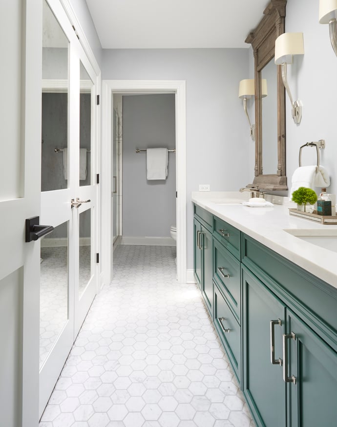 A double sink vanity with bright green cabinetry & hexagon white tiles on the floor - bathroom design by Jasmin Reese, Chicago.