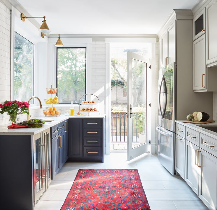 Detail of a large bright galley kitchen designed by Jasmin Reese: red Persian runner, marble flooring and countertops, Chicago.
