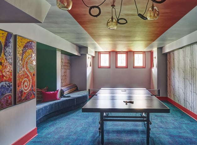 A large basement game room designed by Jasmin Reese, Chicago: wall seating, color, ping-pong table. 