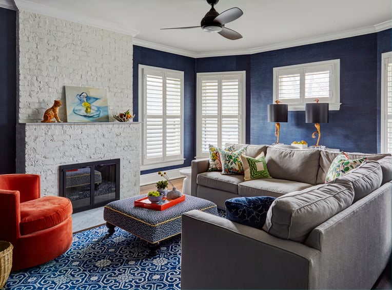 A small cozy living room designed by Jasmin Reese: gray sectional, orange velvet circular chair, cornflower blue walls. 