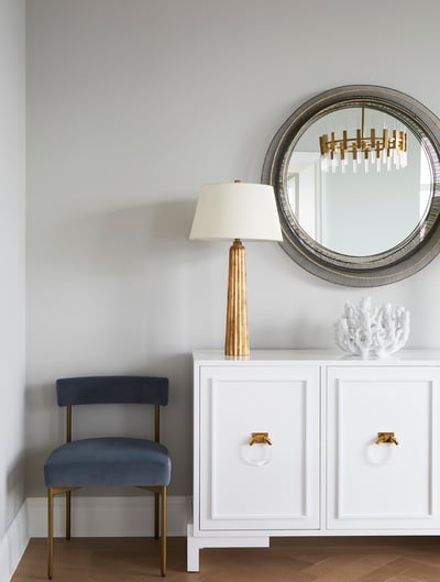 A formal dining room detail by Jasmin Reese with a small gray velvet chair and rose gold lamp, Chicago. 