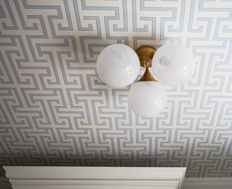 A dining room detail by Jasmin Reese: Greek meander pattern ceiling with a three-globe light fixture, Chicago. 