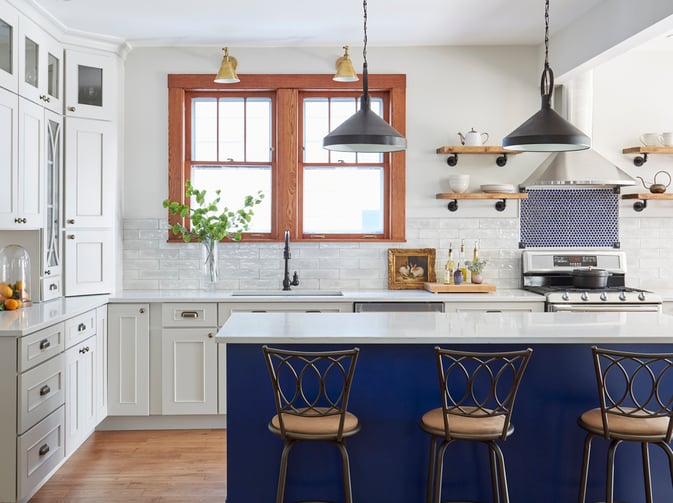 A French kitchen design by Jasmin Reese: white cabinets, marble countertops, blue island, black drop lights, Chicago. 