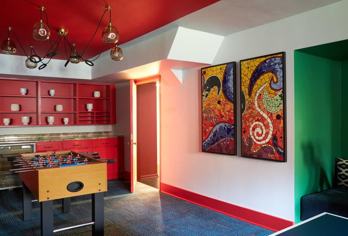 A colorful basement game room designed by Jasmin Reese Interiors, Chicago: foosball, art, primary colors, playful lighting. 