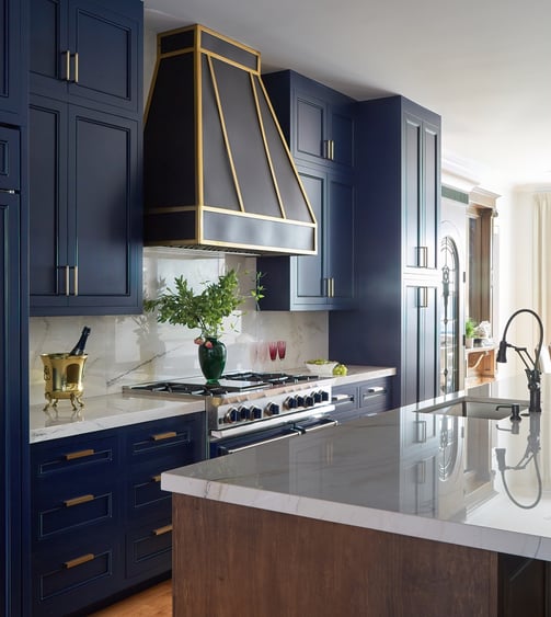 A side view of a kitchen design by Jasmin Reese with bright blue cabinetry and dark wood stove vent, Chicago. 