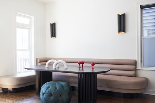 A dining room designed by Jasmin Reese with tan leather booth seating, turquoise puff chair, and ornate black table, Chicago. 