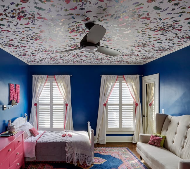 A whimsical child's room designed by Jasmin Reese, Chicago: butterfly wallpaper ceiling, bright blue walls, hot pink details, large cream sofa. 