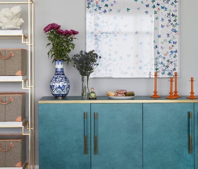 Delightful details of a living room designed by Jasmin Reese: butterflies, orange candlesticks, turquoise sideboard, donuts. 