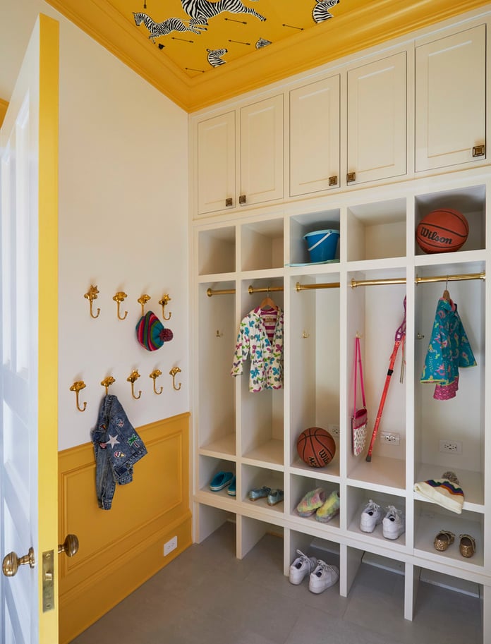 A bright locker room style mudroom with children's shoes and coats stored in cubbies - interior design by Jasmin Reese Interiors, Chicago, USA. 