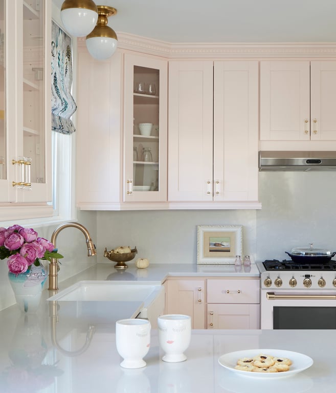 A bright traditional kitchen design by Jasmin Reese with soft pinks, rose gold fixtures, and white accents, Chicago. 