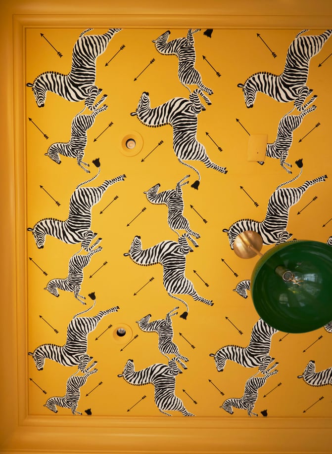 A bright yellow ceiling with zebras and arrows with a bright green drop light - interior design by Jasmin Reese Interiors, Chicago, USA. 