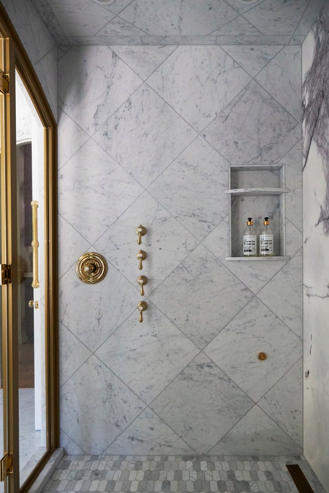  Inside a large walk-in marble & brass shower in a bathroom designed by Jasmin Reese, Chicago. 