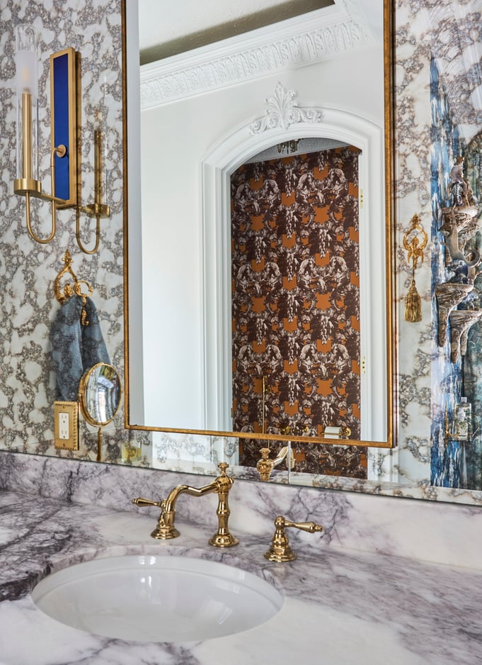 Detail of a marble top vanity with foil mirror & unique brass sunburst fixtures in a bathroom designed by Jasmin Reese, Chicago. 